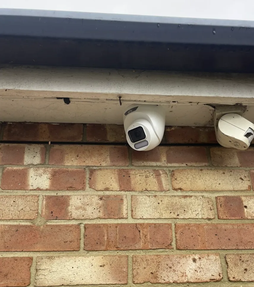 Two CCTV cameras mounted under a soffit on brick